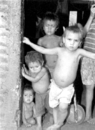 Niños descalzos, en la entrada de una casa de tierra